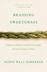 Book cover for Braiding Sweetgrass by Robin Wall Kimmerer. Indigenous Wisdom, Scientific Knowledge, and the Teaching of Plants. "A hymn of love to the world" as quoted by Elizabeth Gilbert. The image is of a single braided grass laying horizontally across the a plain beige background.