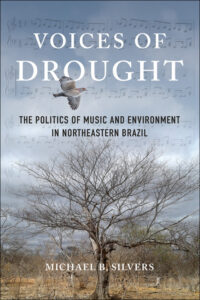 Book cover for Voices of Drought by Michael B. Silvers. The politics of music and environment in Northeastern Brazil. Image includes a bare tree in the foreground and a grey sky with transparent music score in the background.